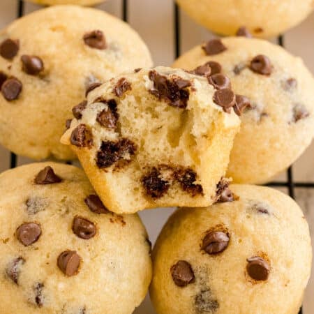 Close-up of mini chocolate chip muffins, one cut open to show melty chocolate chips inside.