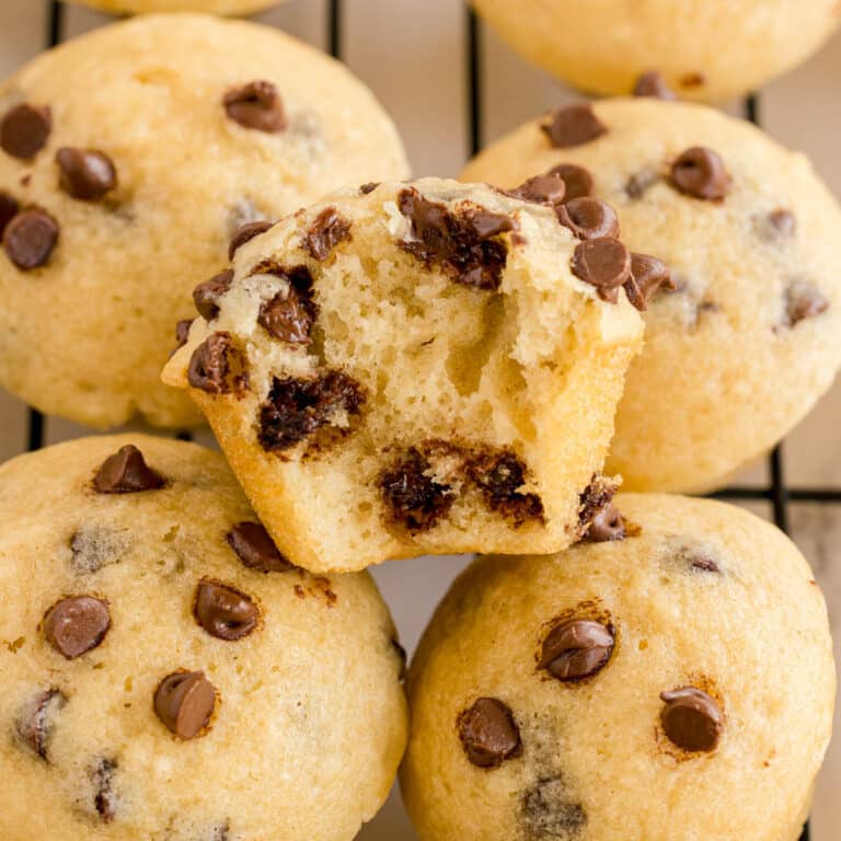 Close-up of mini chocolate chip muffins, one cut open to show melty chocolate chips inside.