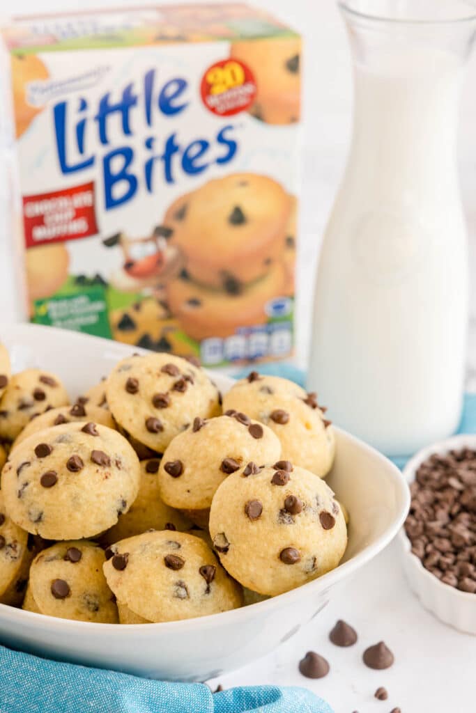 Bowl of mini chocolate chip muffins in front of a milk bottle and a box of Little Bites muffins.