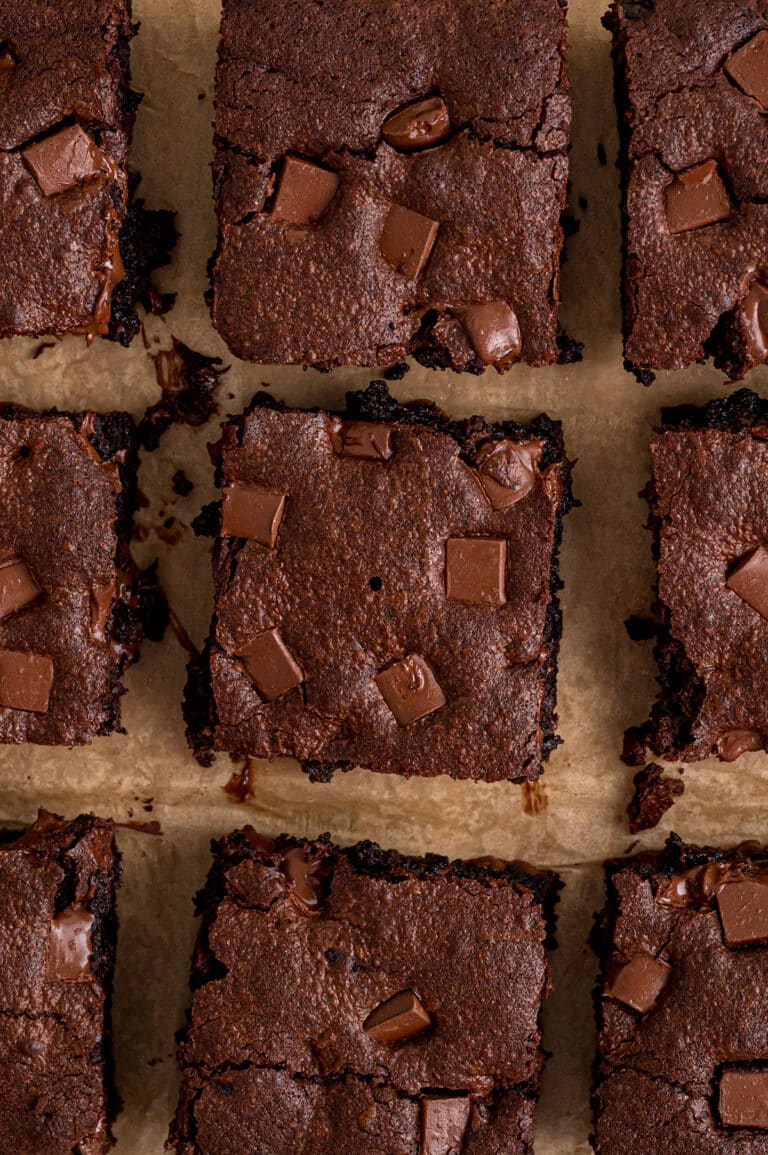 Overhead view of neatly sliced chocolate chunk brownies on parchment paper.
