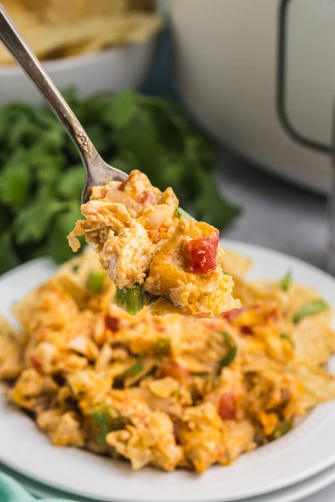 Fork holding a bite of King Ranch chicken above a full plate.