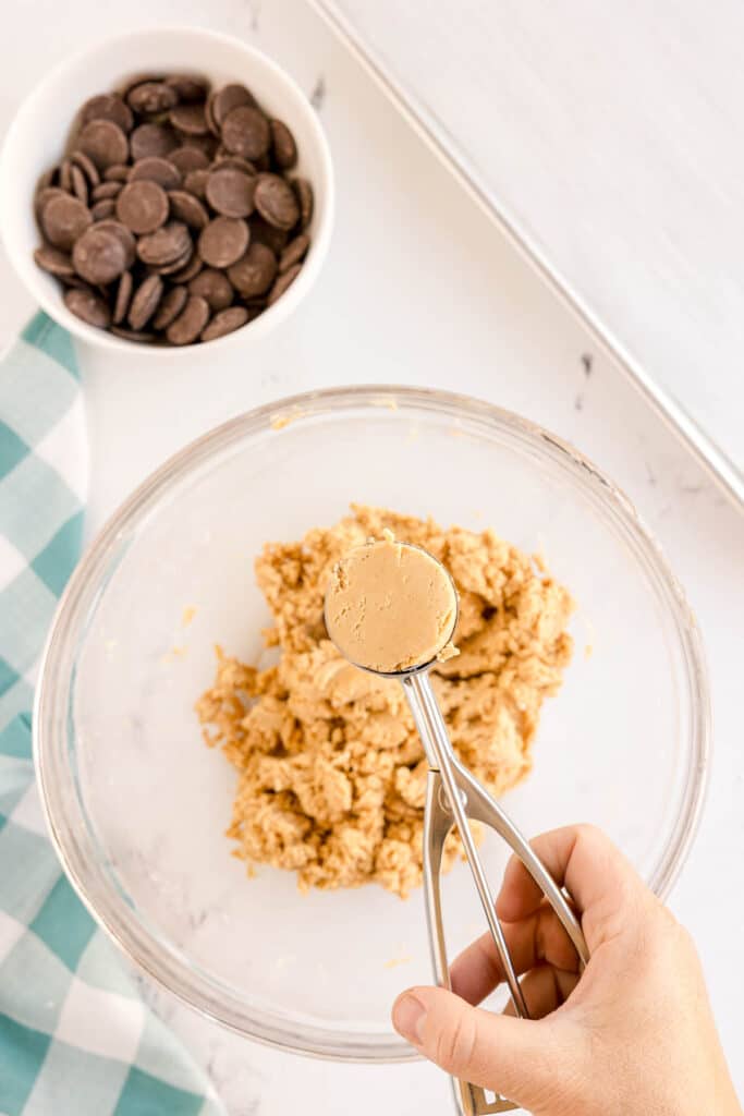 Scooping peanut butter mixture with a cookie scoop.