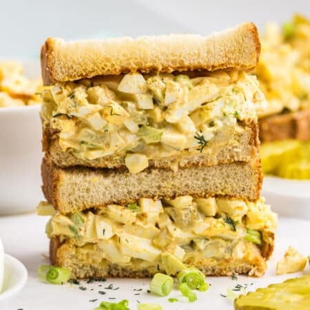 A stacked egg salad sandwich filled with creamy dill pickle egg salad.