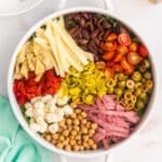 Colorful antipasto salad ingredients arranged neatly in a white bowl.