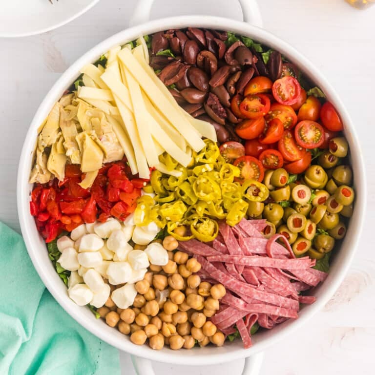 Colorful antipasto salad ingredients arranged neatly in a white bowl.