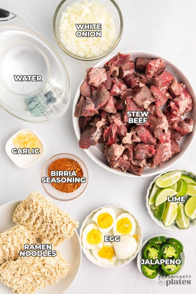 Flat lay of labeled ingredients for birria ramen including beef, noodles, lime, and more.