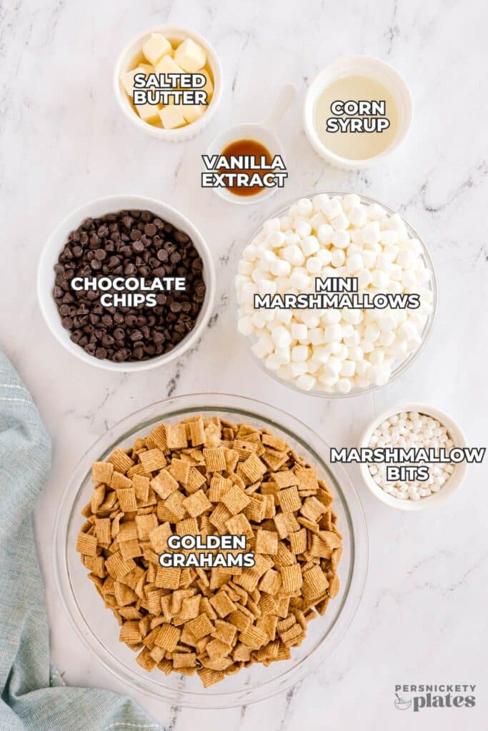 Flat lay of ingredients for Golden Grahams s’mores bars labeled in white text.