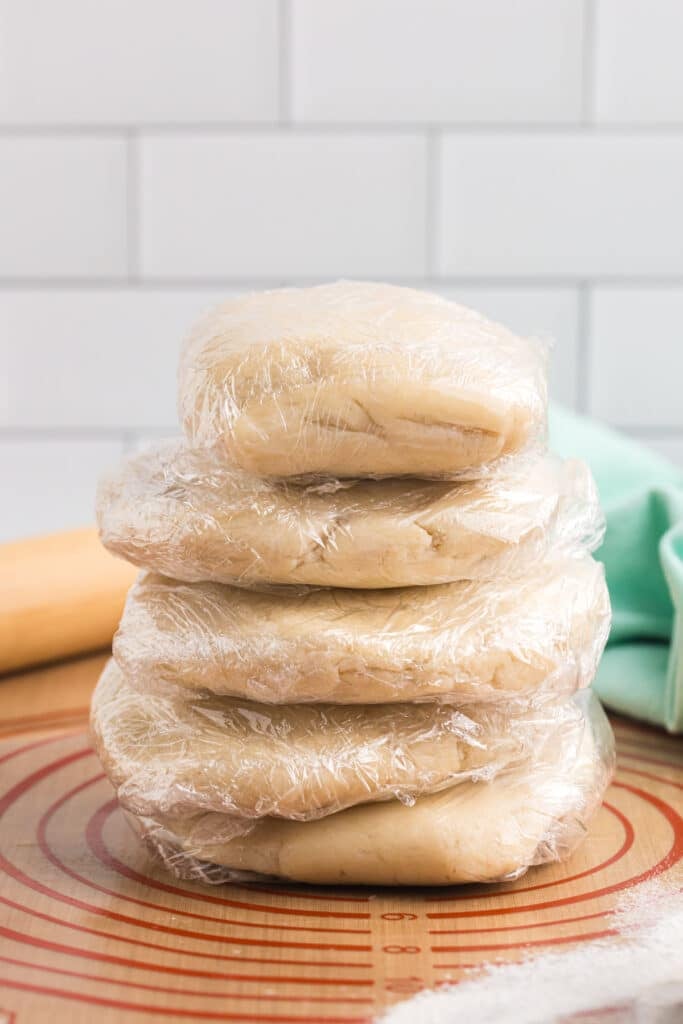 Stack of pie dough discs wrapped in plastic wrap.