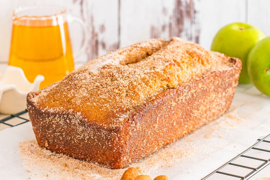 Cinnamon-sugar apple cider donut bread loaf on cooling rack.