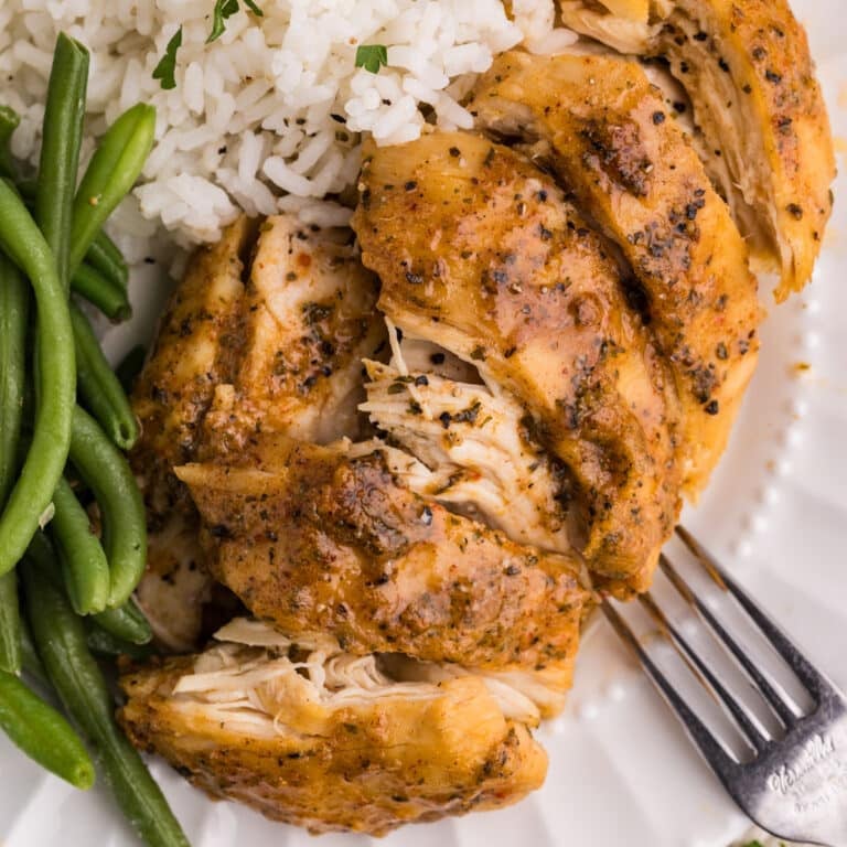 Square close-up of chicken, rice, and green beans on a plate.