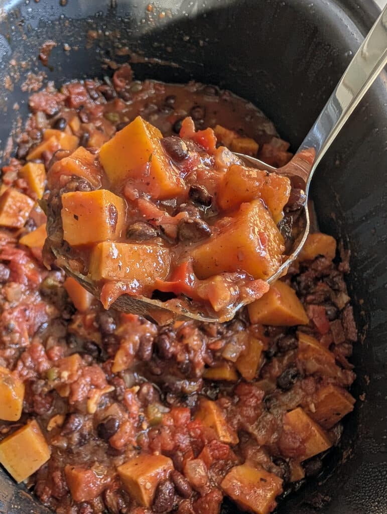 A ladle lifting chili from a slow cooker.