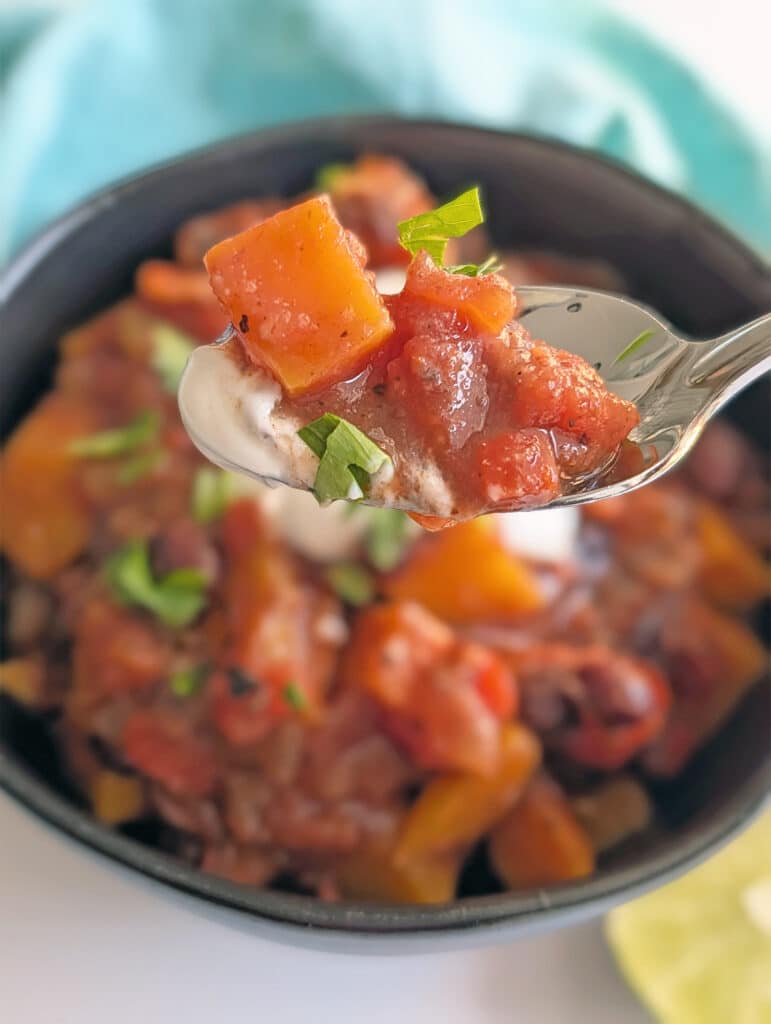 A spoonful of chili lifted above a bowl.
