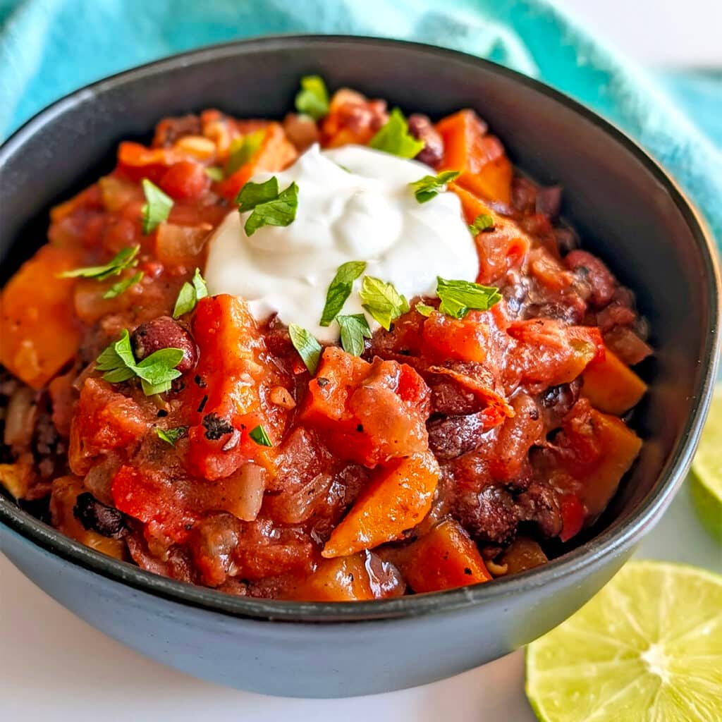 A bowl of chili topped with sour cream and herbs.