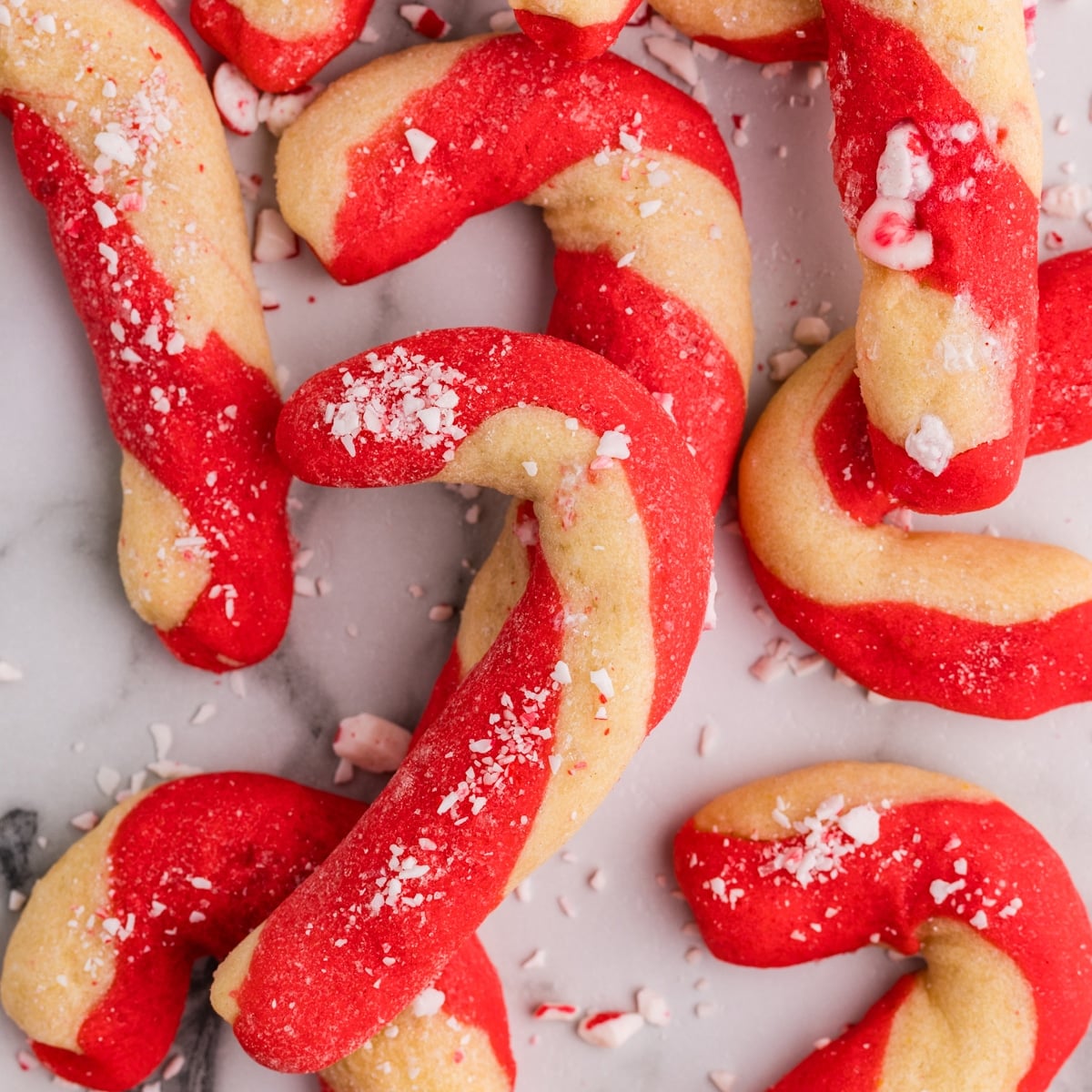 Baked red and white candy cane cookies sprinkled with crushed candy.