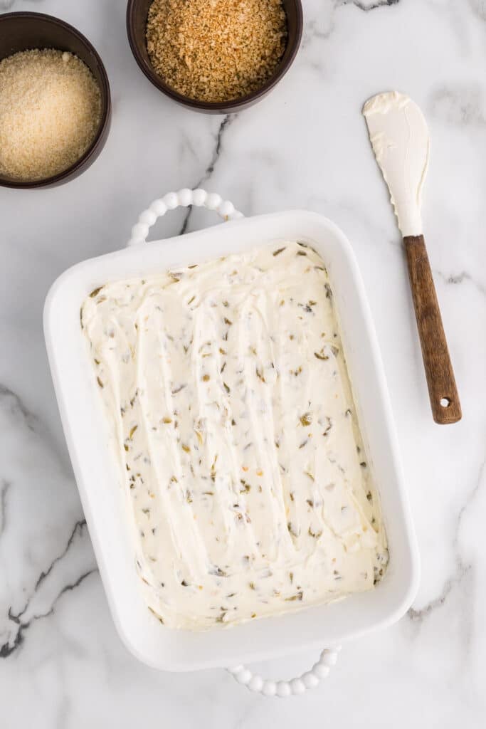 Creamy jalapeño dip spread in a white baking dish.