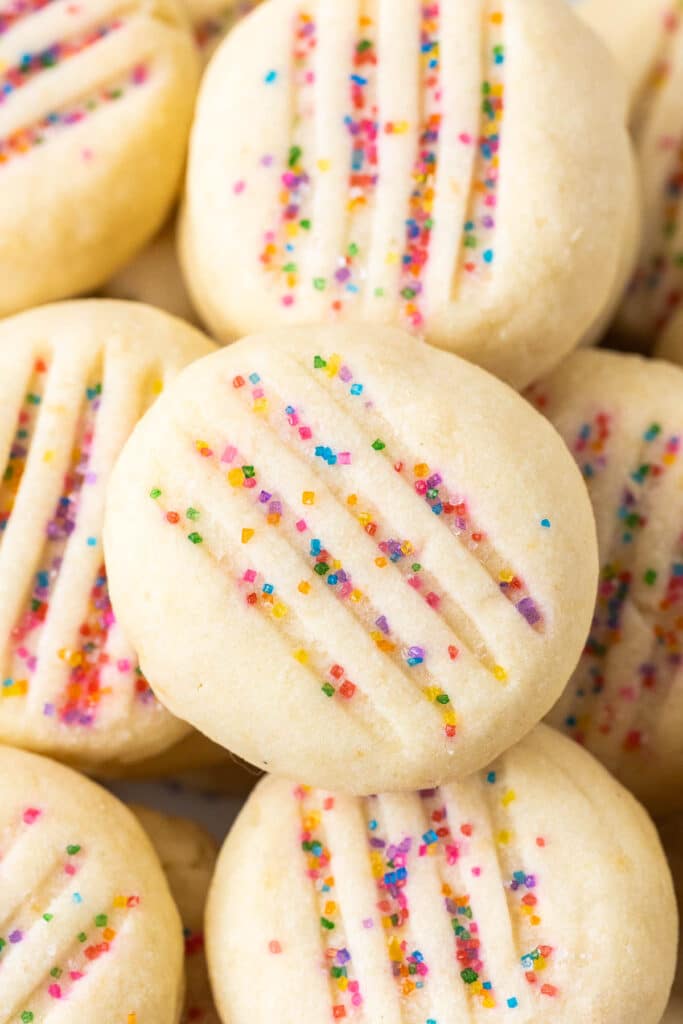 Close-up of round shortbread cookies topped with rainbow sprinkles.