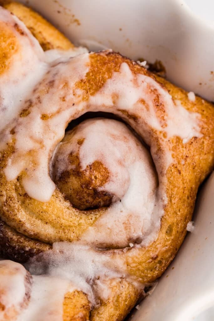 Close-up of an iced cinnamon roll in a baking dish.