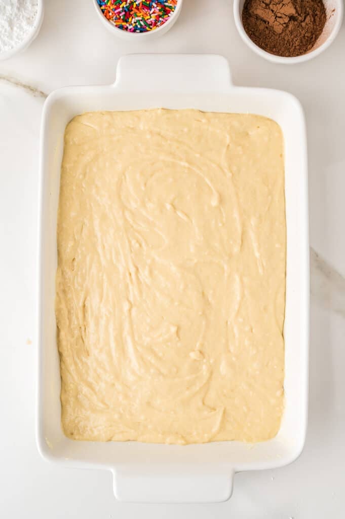 Yellow cake batter spread in a white rectangular baking dish.
