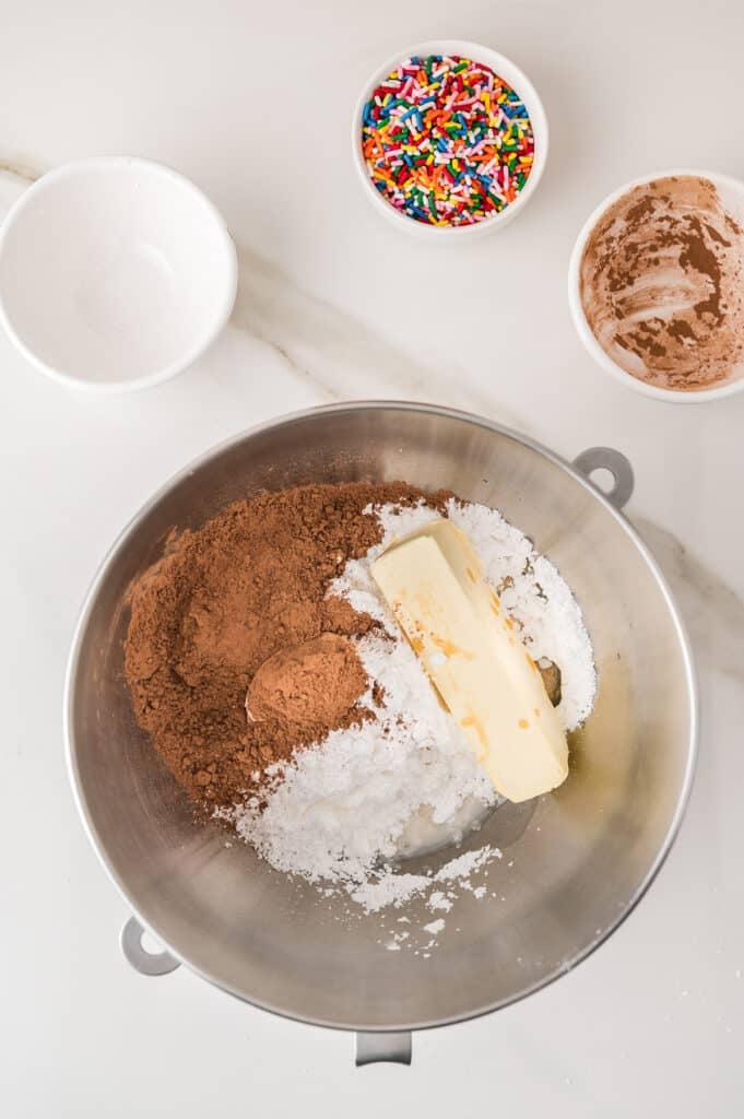 Butter, cocoa powder, and powdered sugar in a mixing bowl.